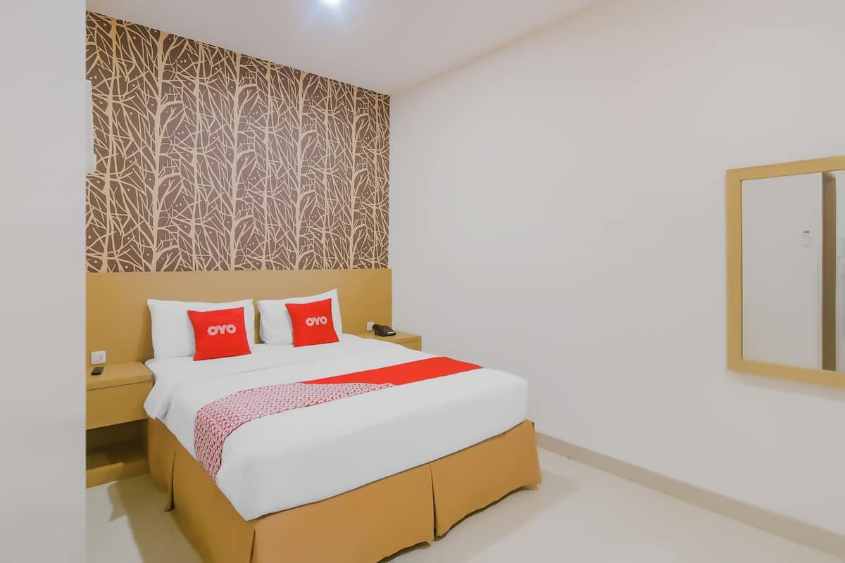 A hotel room with a bed, a nightstand, a wall-mounted mirror, and a patterned wall.