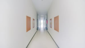 Un pasillo largo y estrecho con paredes blancas y puertas de madera a ambos lados.