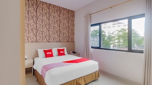 Habitación de hotel con una cama grande, una mesita de noche, un papel tapiz con diseño y una ventana con vistas a edificios.