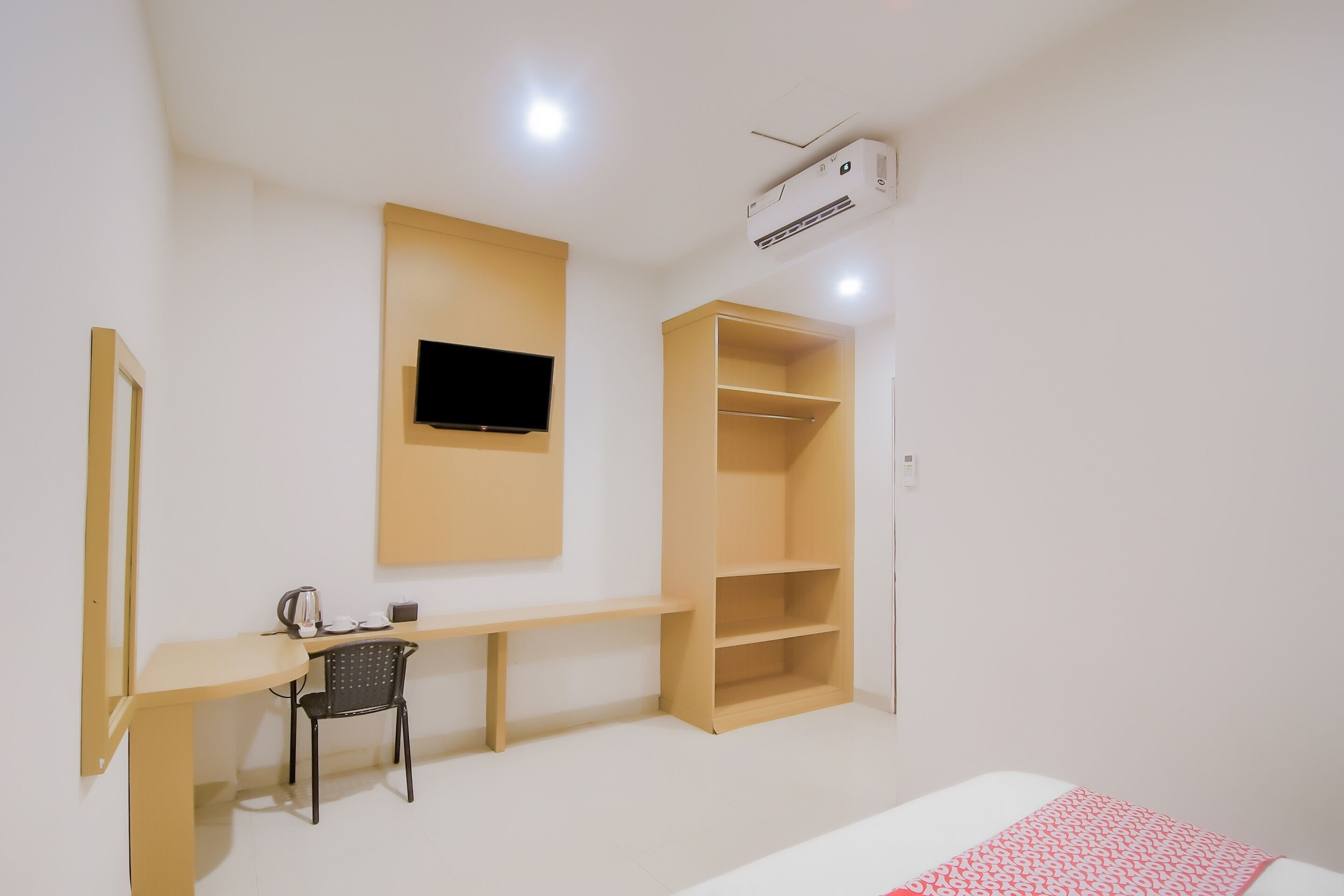 Une chambre à coucher comprenant un lit, un bureau, une chaise, un téléviseur fixé au mur et une armoire.