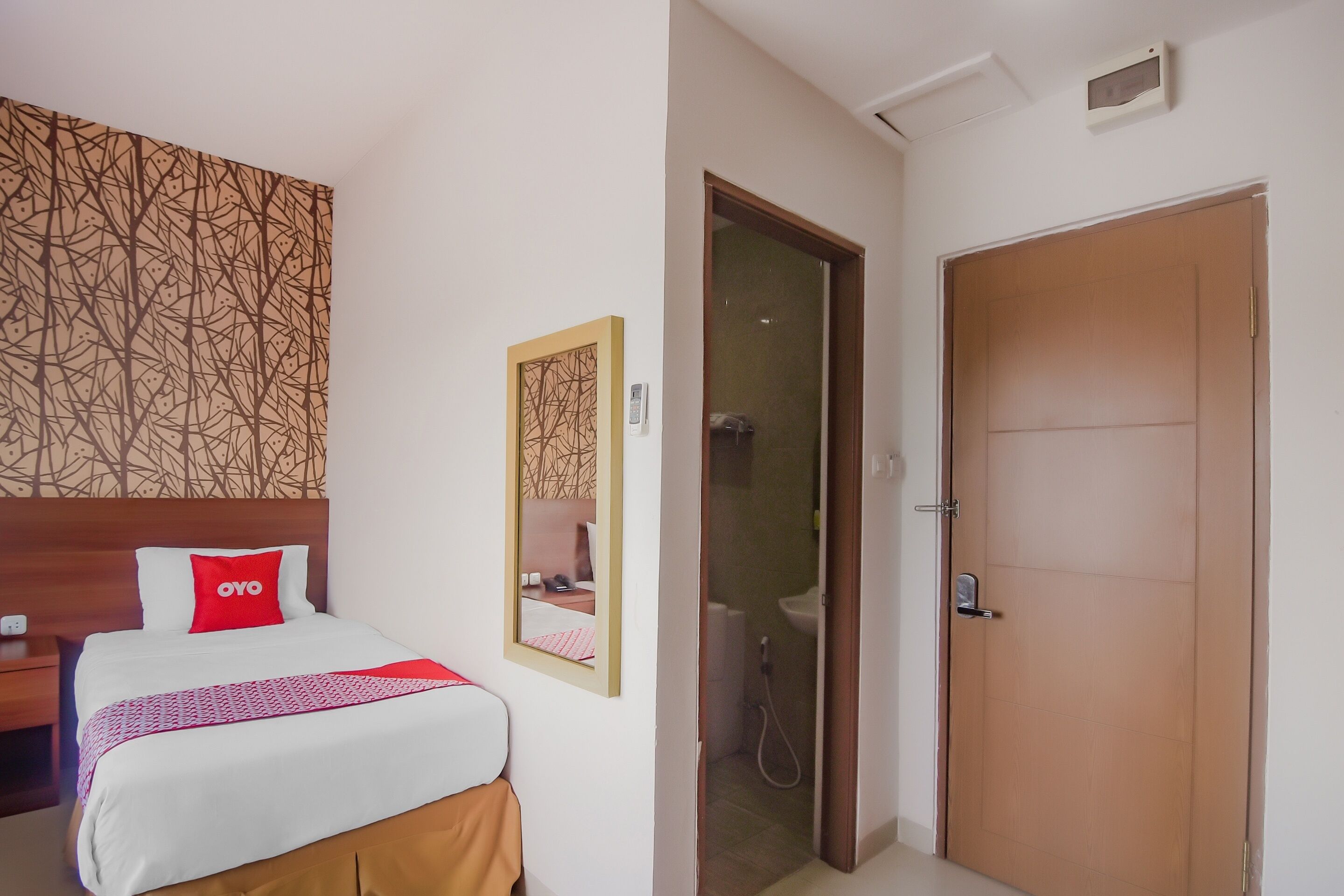 A hotel room with a bed, a nightstand, a mirror, a shower, and a wooden door.