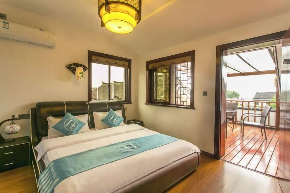 Ein Schlafzimmer mit Bett, Nachttisch und Blick auf einen Balkon.