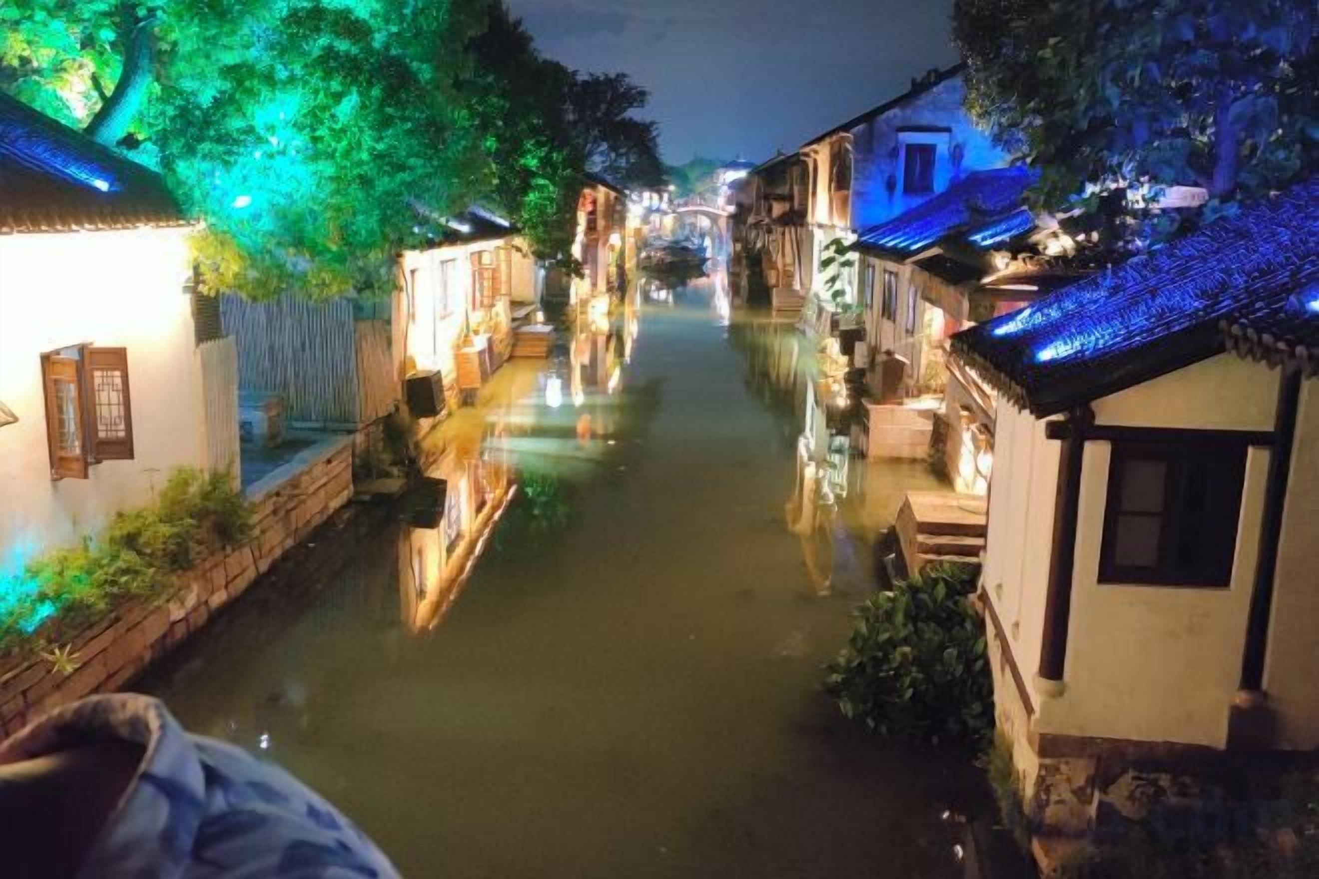 A narrow waterway flanked by traditional buildings with illuminated rooftops.