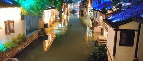A narrow waterway flanked by traditional buildings with illuminated rooftops.