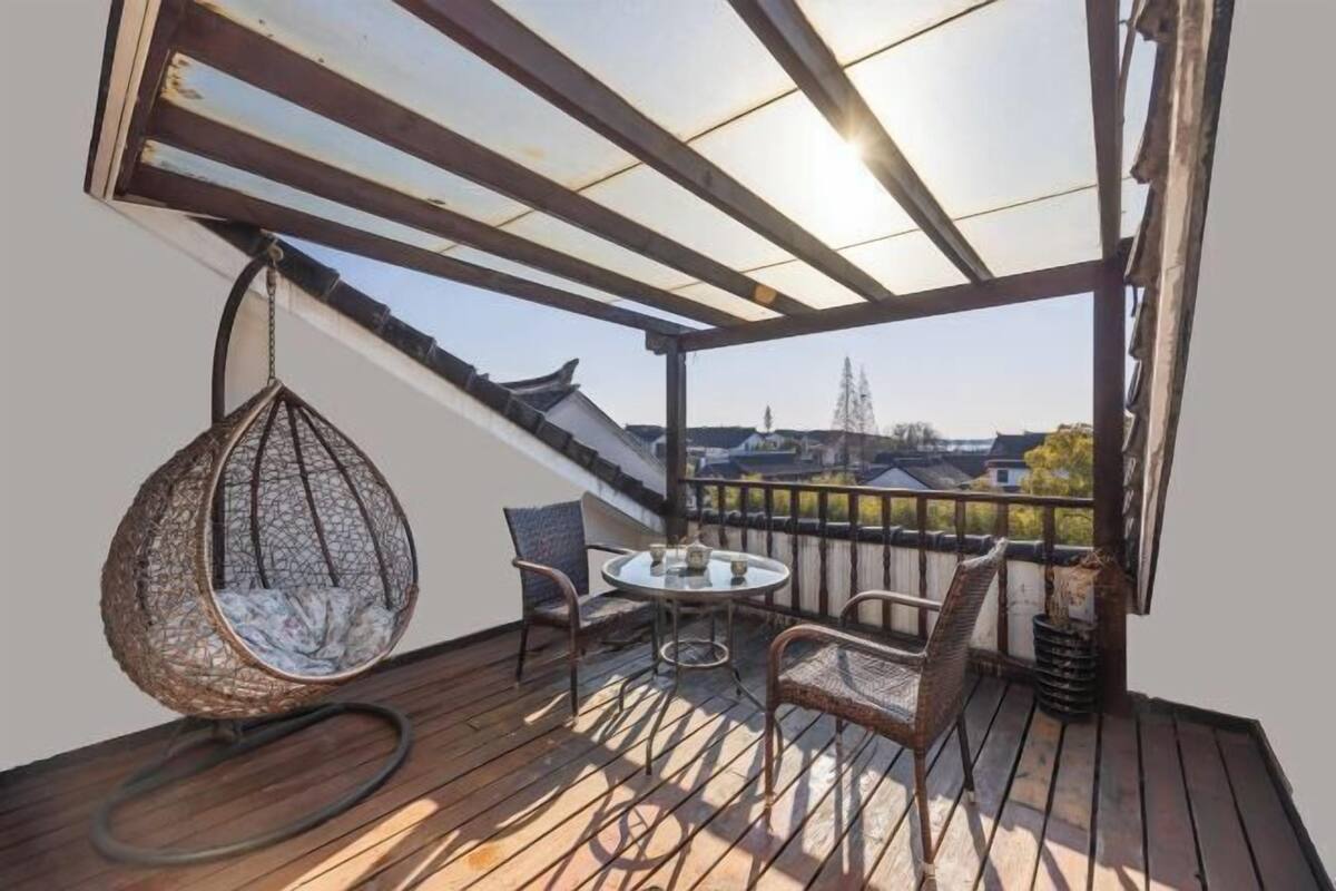 Eine Holzterrasse mit einer Hängematte, einem runden Tisch und zwei Stühlen.