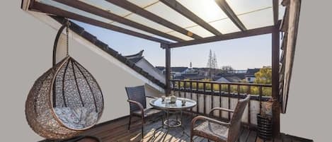 A wooden deck with a hanging chair, a table, and chairs.
