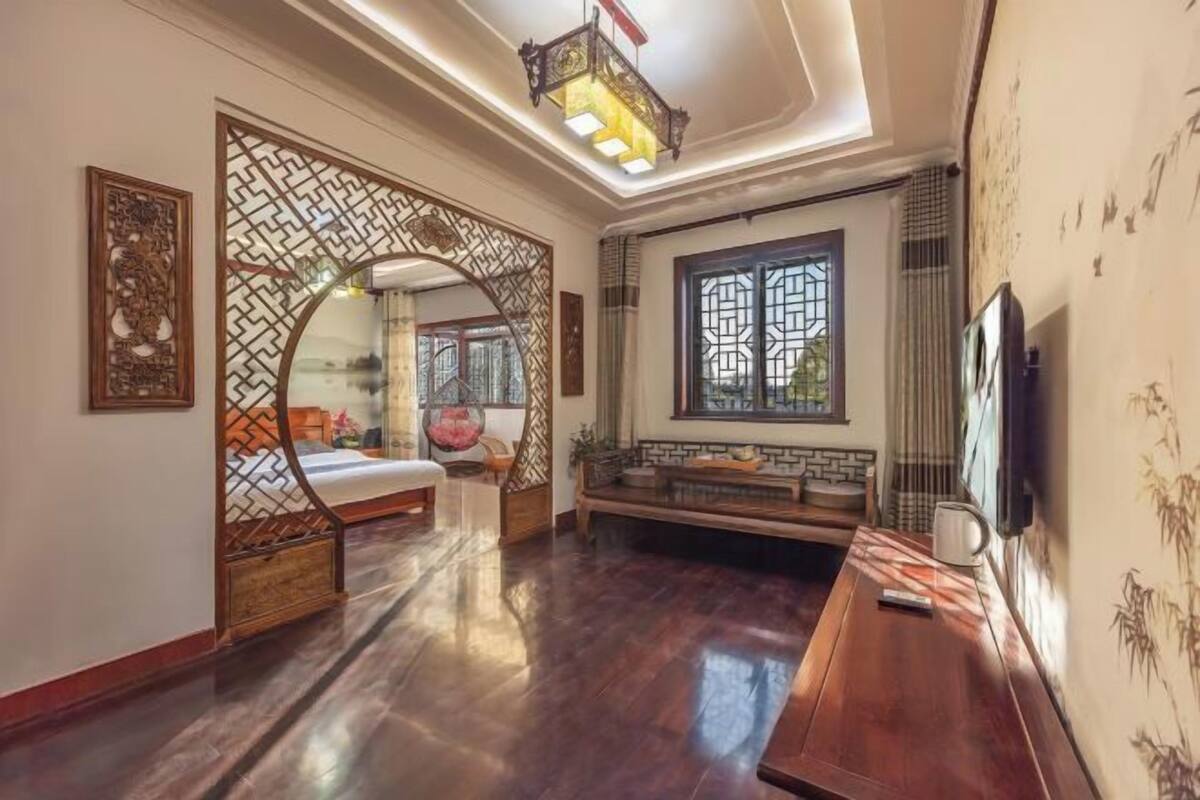 Ein traditionell eingerichtetes Zimmer mit Bett, Sofa, Fernseher und einem Zierdekor.