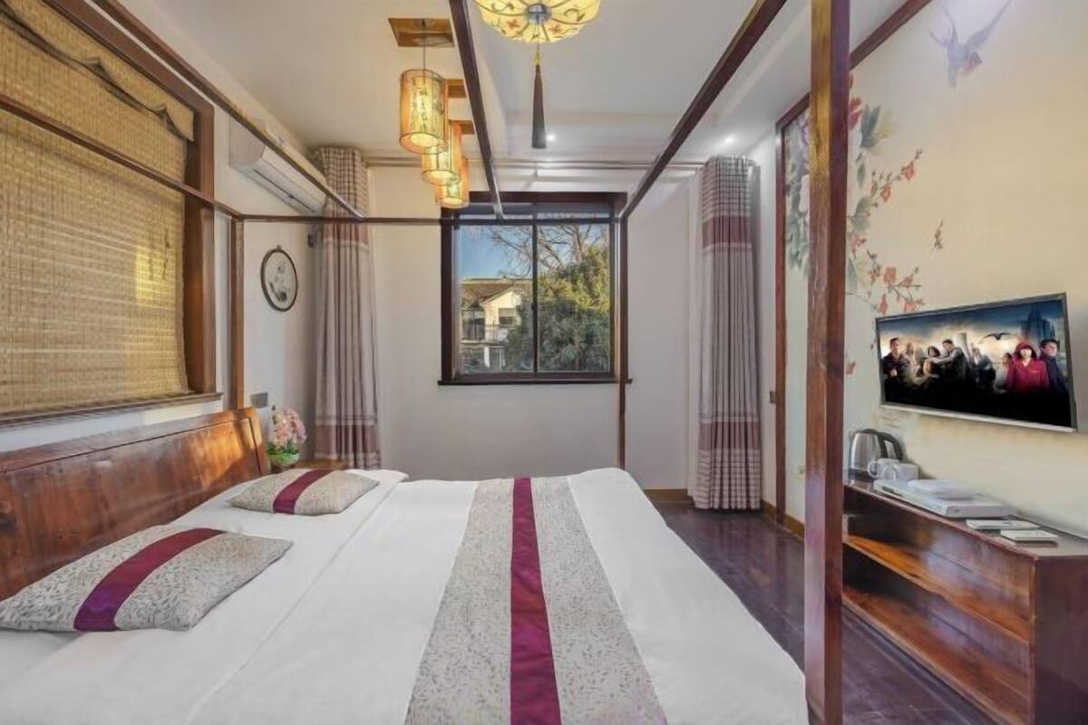 Ein Schlafzimmer mit Bett, Vorhängen, einem Fernseher und einem Fenster.