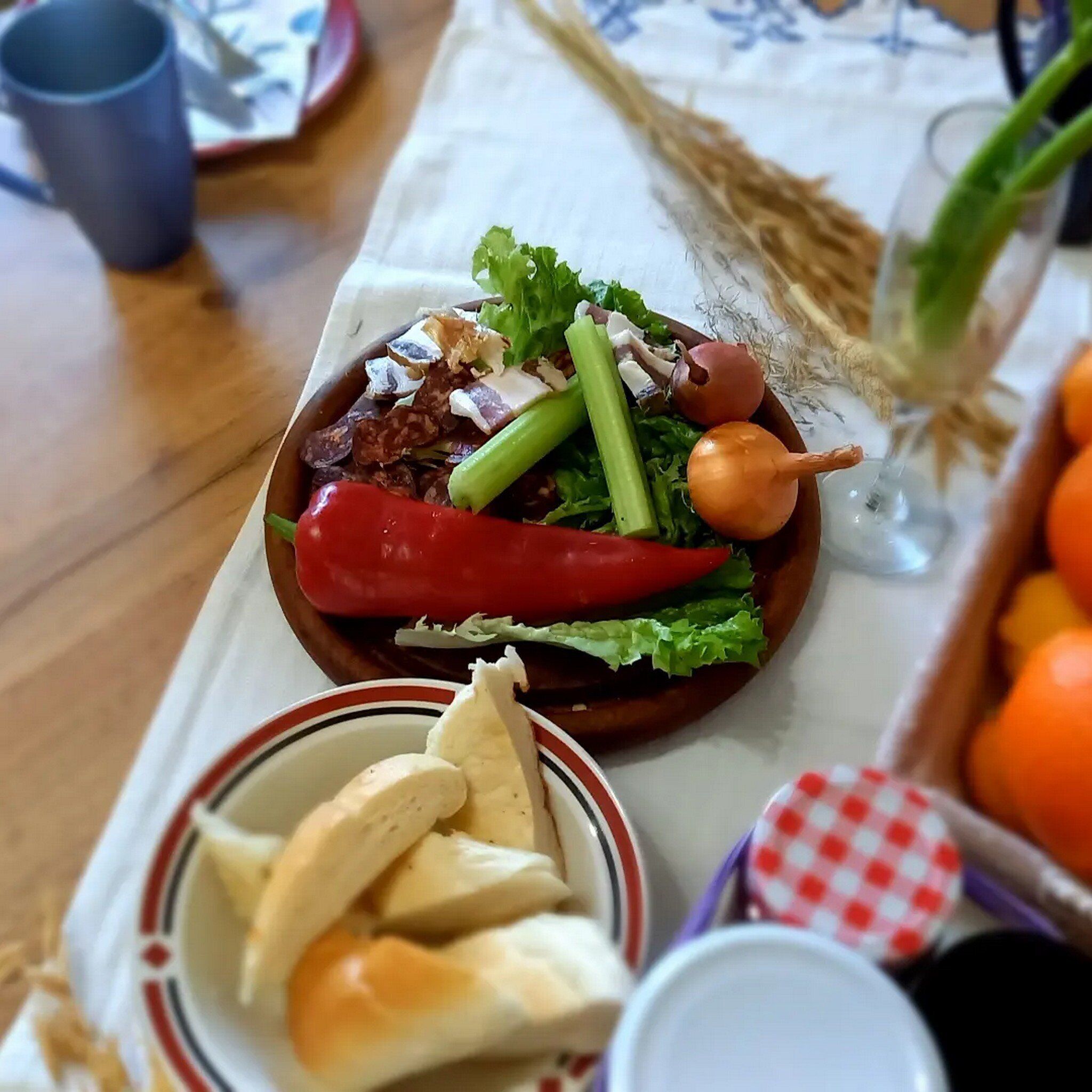 Een tafel met een salade, brood en een glas water.