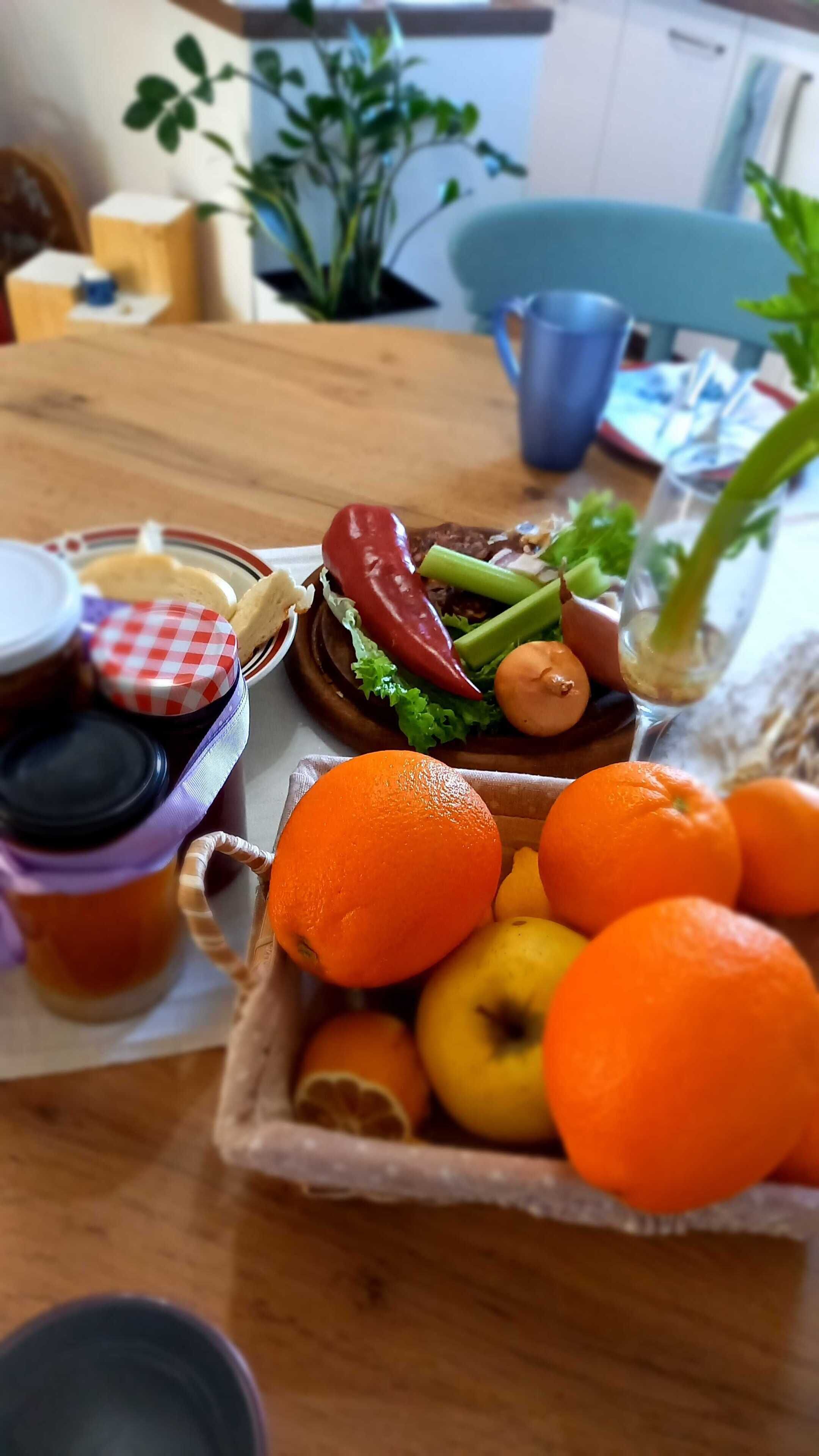 Une table en bois sur laquelle sont disposés divers fruits et légumes, notamment des oranges et un panier de citrons.