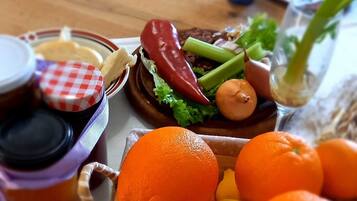 Una mesa de madera con una variedad de frutas y verduras, incluyendo naranjas y una cesta de limones.