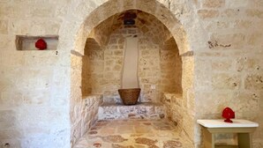 A stone-walled alcove with a bench and a basket.