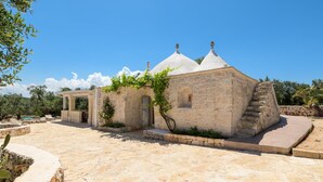 A stone building with a covered porch and a staircase leading to a higher level.