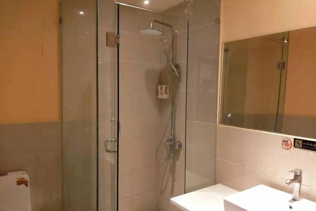 A modern bathroom with a glass-enclosed shower, a white sink, and a mirror.