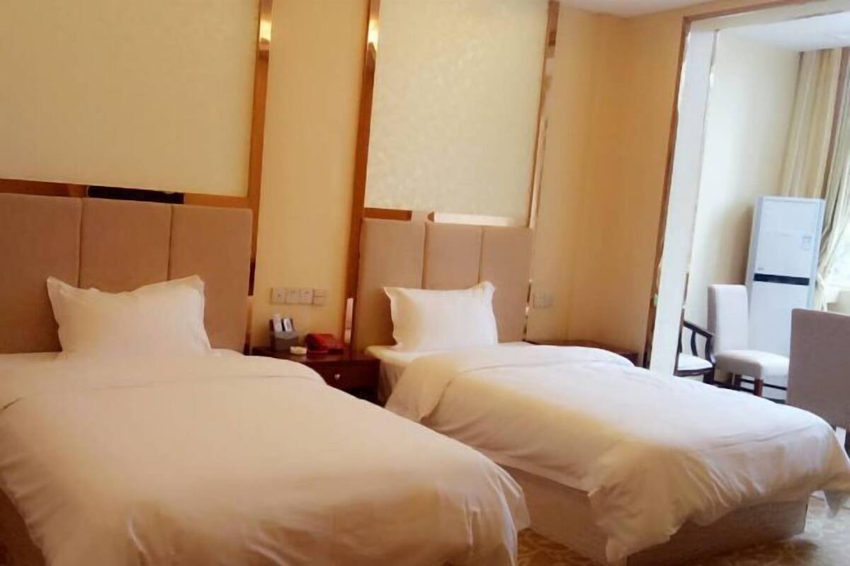 A hotel room with two beds, a small desk, and a chair.