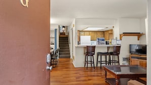 A compact kitchen with a microwave, bar stools, and a television. - Heavenly Chairview Condo 2 Bedroom Home by RedAwning (Stateline)
