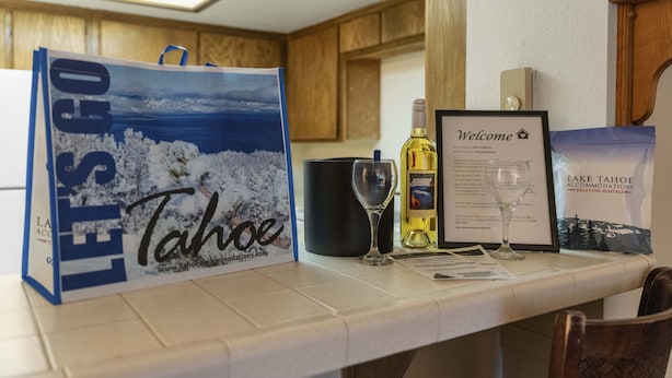 A table with a welcome sign, a glass of wine, a bottle of wine, a framed welcome sign, and a bag with a Tahoe accommodations advertisement. - Heavenly Chairview Condo 2 Bedroom Home by RedAwning (Stateline)