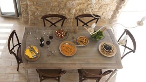 A wooden dining table set with plates, glasses, and bottles, surrounded by wooden chairs. - Two Bedroom Villa With Attic - Dalia (West Mani)