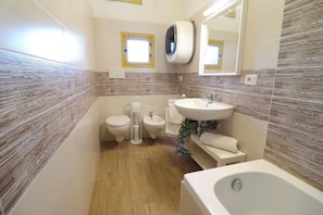 A bathroom with a toilet, bidet, sink, and bathtub.