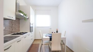Eine moderne Küche mit weißen Schränken, einem Gasherd und einem Fenster mit weißen Jalousien.