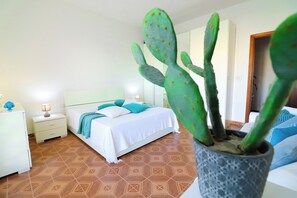 Une chambre à coucher avec un lit, des tables de chevet, un cactus en pot et un sol à motifs.