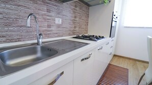 Eine moderne Küche mit Spüle aus Edelstahl, einem Gasherd und weißen Schränken.