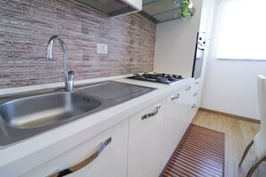 Una cocina moderna con un lavamanos de acero inoxidable, una estufa a gas y armarios blancos.
