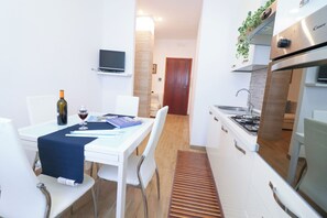 A compact kitchen with white cabinets, a built-in oven, and a dining area with a table and chairs.