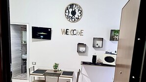 Una cocina moderna con un reloj, un letrero de bienvenida y un pequeño comedor con una mesa y sillas.