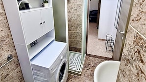 Un baño pequeño con lavadora, inodoro y lavabo.