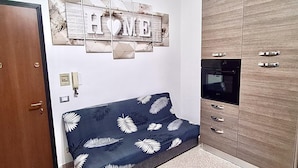Un espacio habitable compacto con sofá, un mueble de madera y un adorno en la pared.