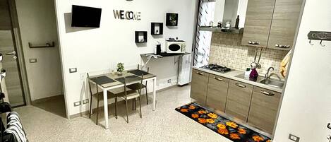 Una cocina moderna con comedor, televisor de pantalla plana y un cartel que dice 'WELCOME'.