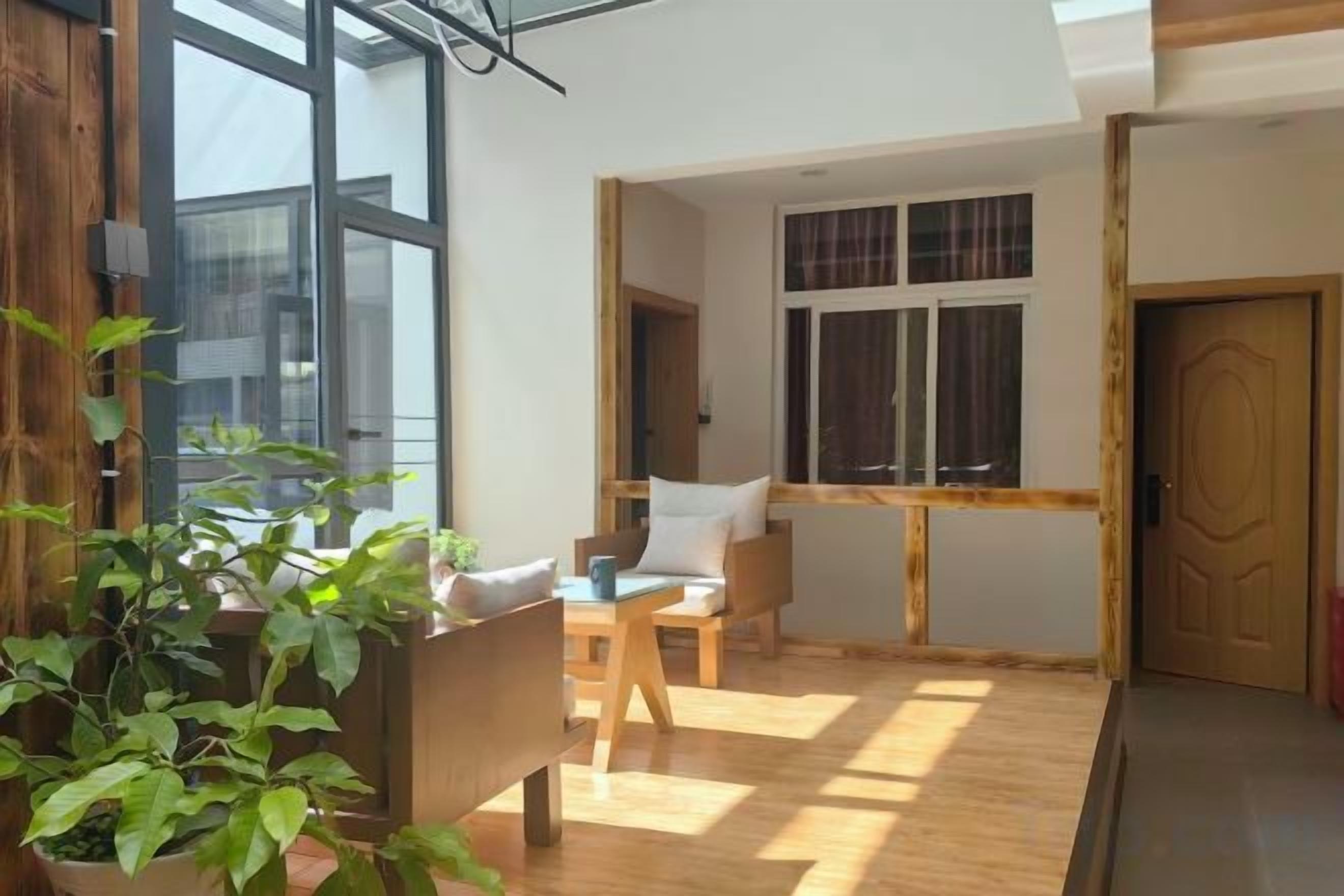 Een kamer met een houten vloer, een eettafel met stoelen, een kamerplant en een raam met gordijnen.