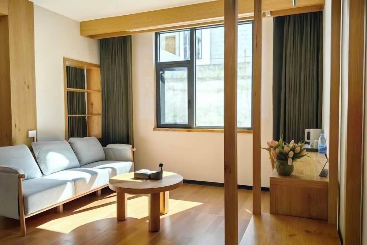 A modern living room with a sofa, a round coffee table, and a small side table with a vase of flowers.