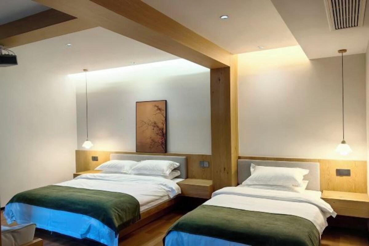 Una habitación de hotel moderna con dos camas, cabeceros de madera e iluminación colgante.
