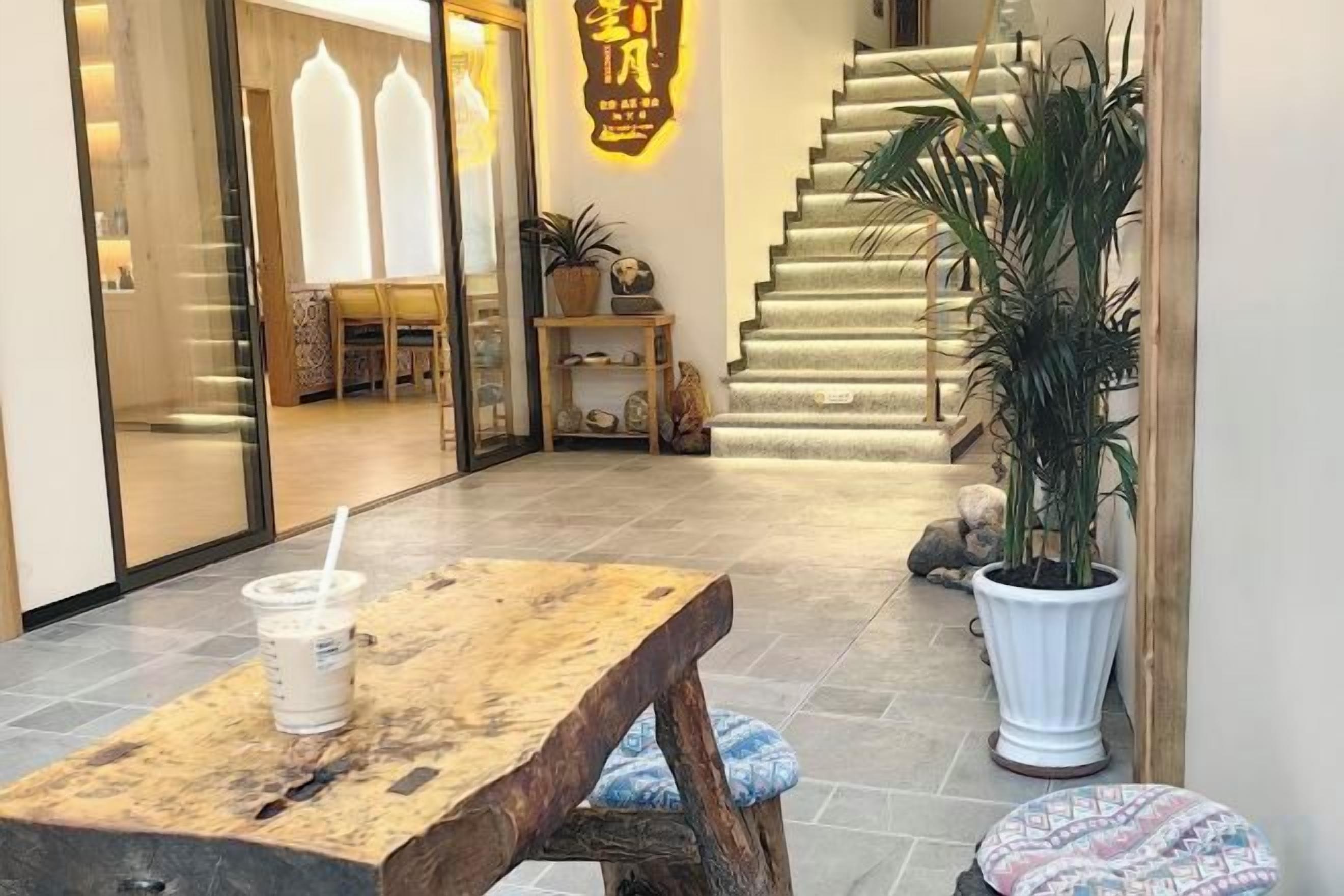 A reception area with a wooden bench, a potted plant, and a staircase leading to an upper floor.