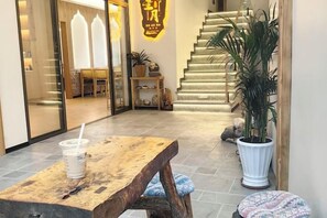 Un área de recepción con un banco de madera, una planta en maceta y una escalera que sube a un piso superior.
