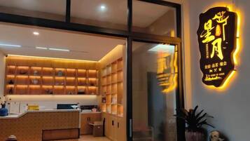 A modern interior with a reception desk, shelves with items, and a neon sign.