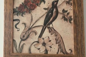 A framed artwork of a bird perched on a branch with flowers. - Xingyue Courtyard-Style Hotel (Xiaojin)