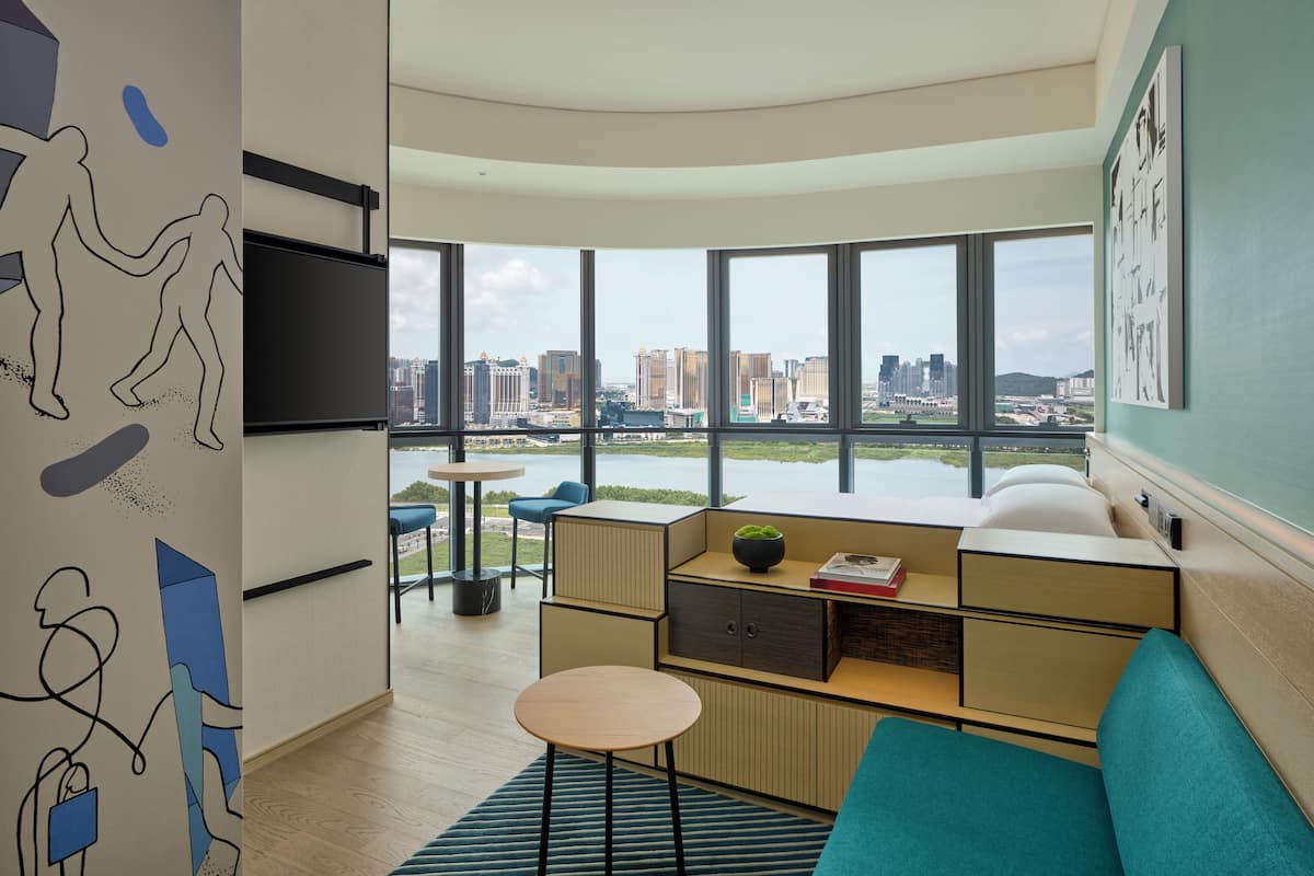 A modern living room with a city view, a flat-screen TV, a sofa, a small table, and a coffee table.