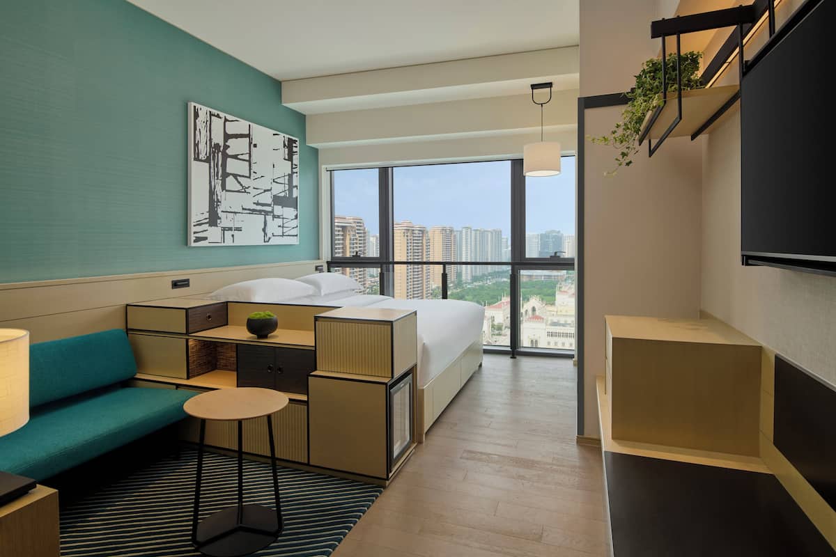 A modern hotel room with a large bed, a sofa, a small table, and a TV.