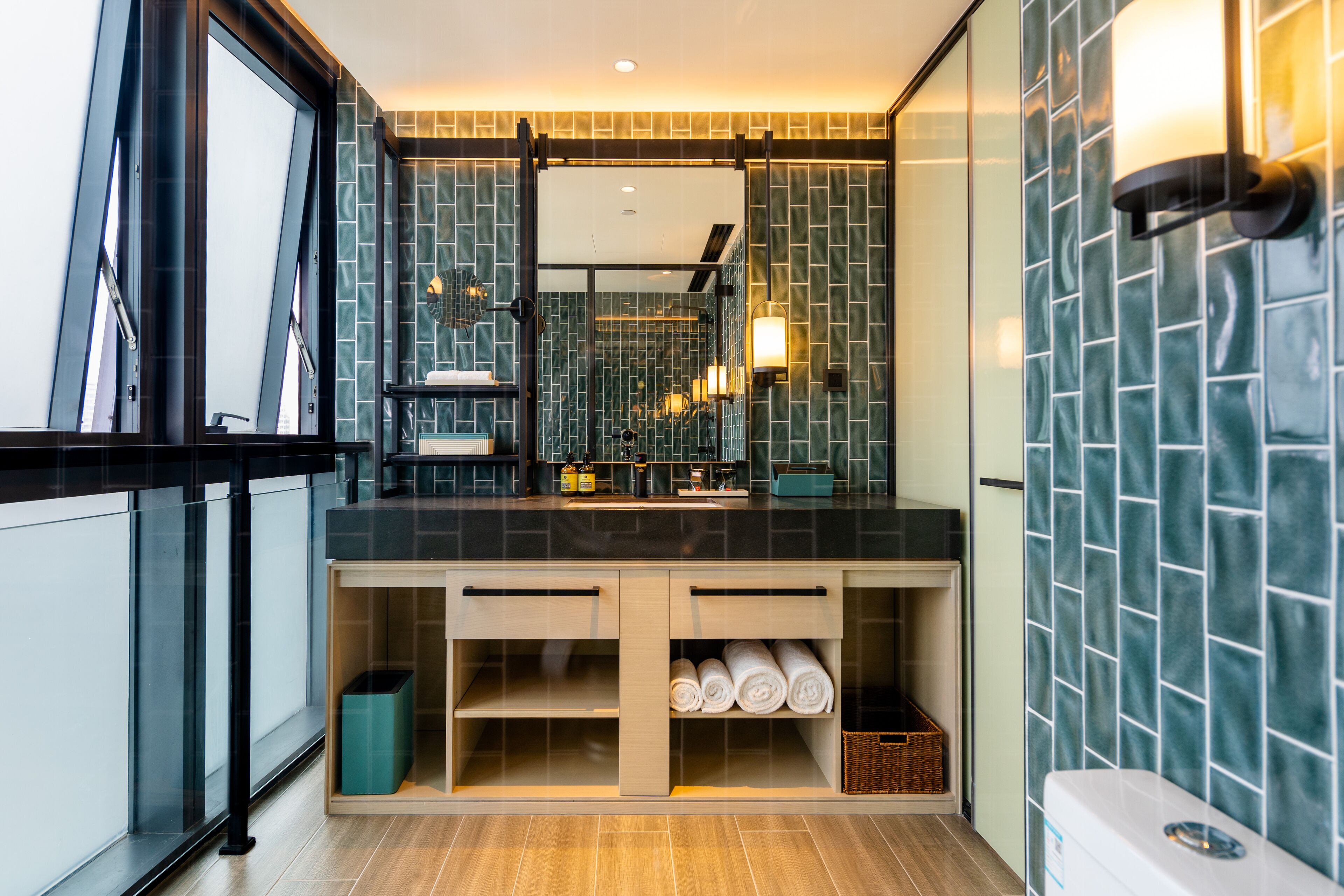 Un baño moderno con encimera negra, cabina de ducha de vidrio y salpicadero de azulejos.
