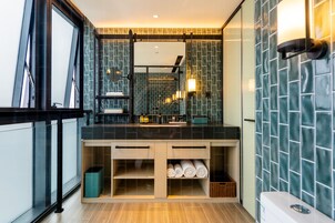 Un baño moderno con encimera negra, cabina de ducha de vidrio y salpicadero de azulejos.