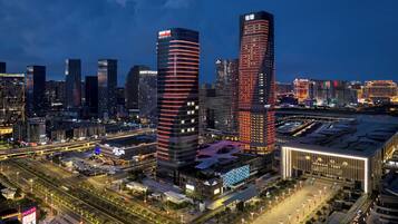 A cityscape with modern skyscrapers, including a prominent building with illuminated lines and another with a distinctive vertical design.