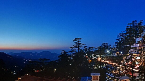 A hotel with multiple floors, a prominent entrance, and a view of the surrounding mountains. - Hotel Baljees Regency (Shimla)