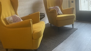 A room with two yellow armchairs, a black rug, wooden walls, and two framed pictures. - Cozy is (Pont-Audemer)