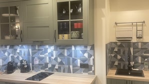 A modern kitchen with light green cabinets, a geometric backsplash, and a wooden countertop. - Cozy is (Pont-Audemer)