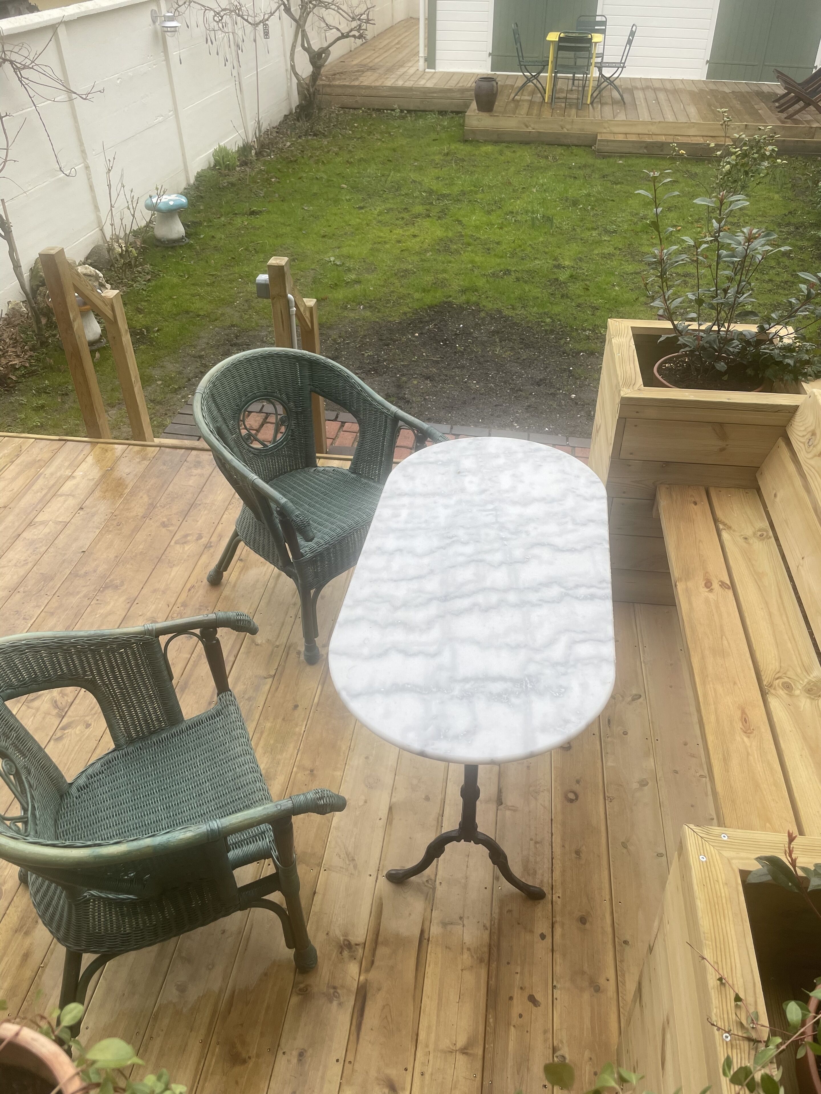 A wooden deck with a round table and two wicker chairs.