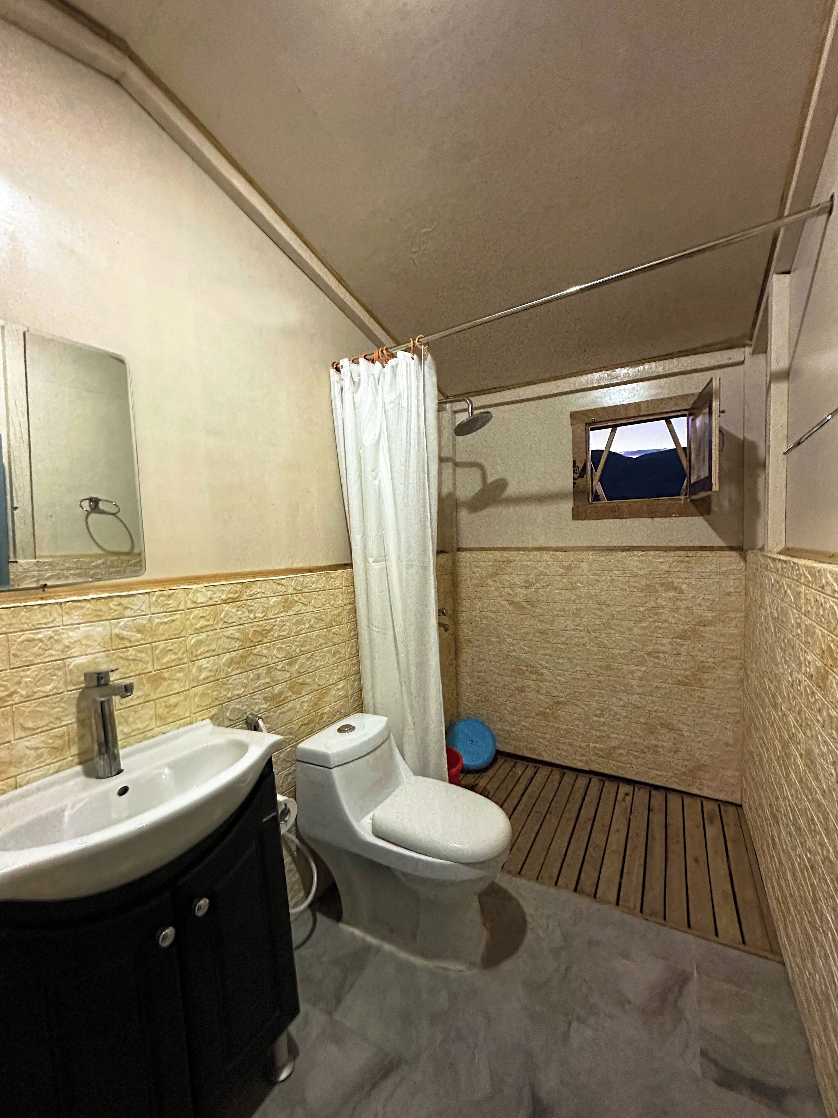 A compact bathroom with a sink, toilet, and shower.