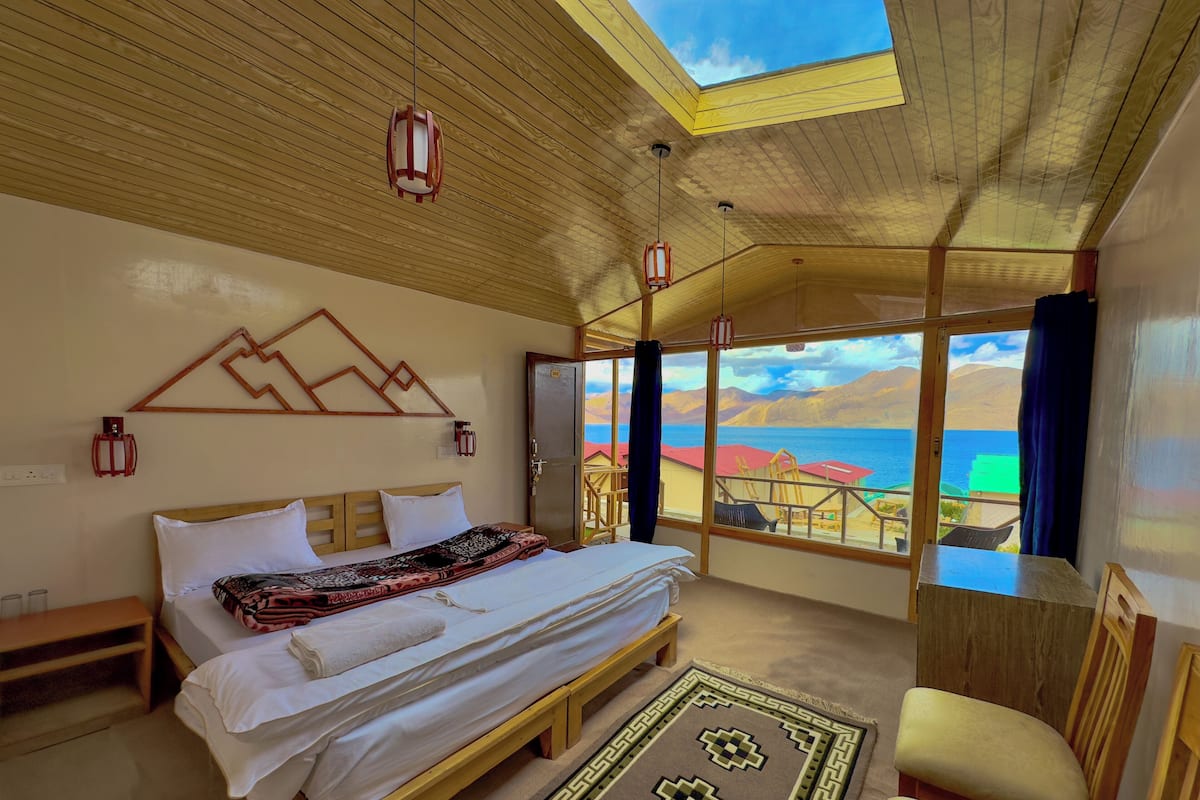 Un dormitorio con una cama grande, cabecera de madera y vista al mar.